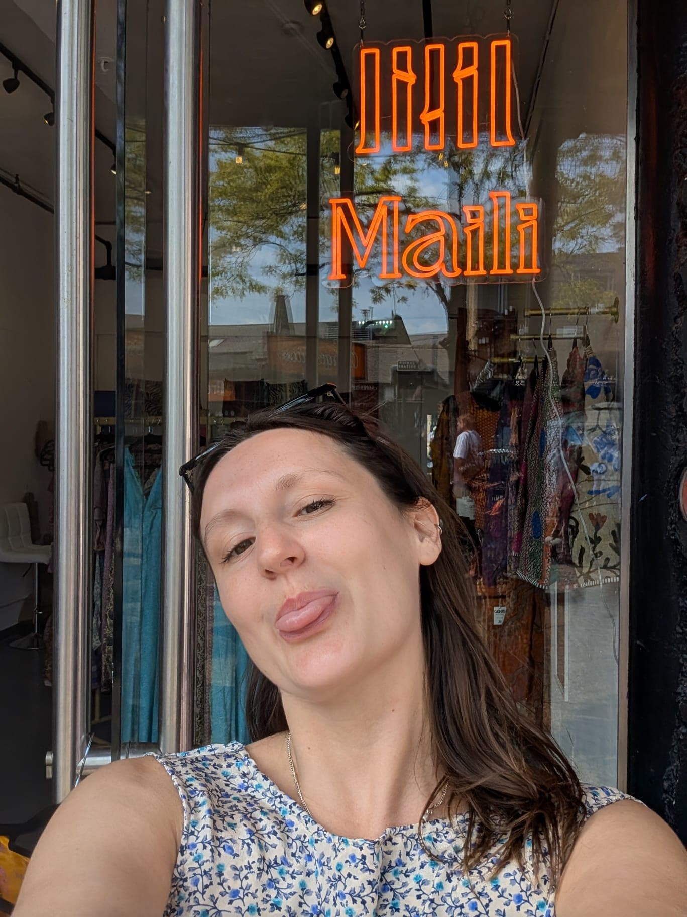 Camille outside the finished Maili storefront, lit by the neon sign